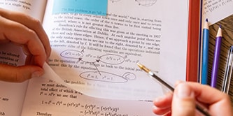 Un étudiant annotant un manuel avec une note Post-it® transparente, surlignant des équations mathématiques
